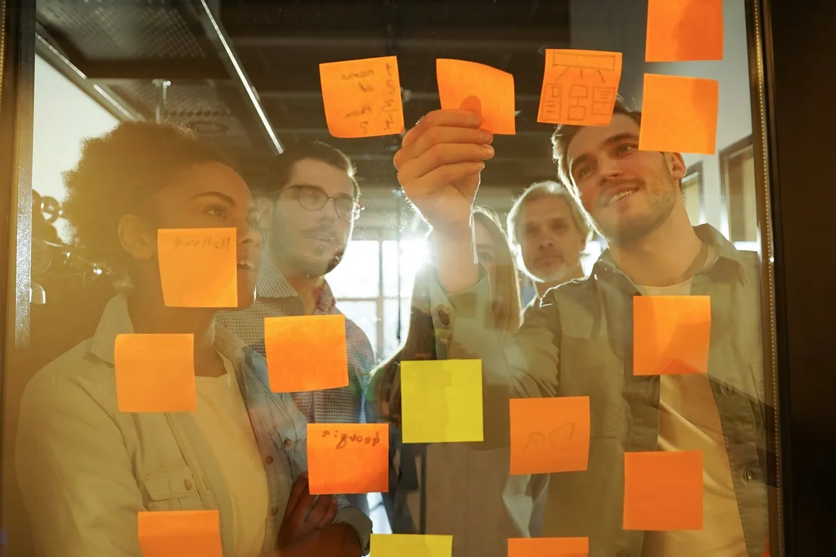 Team klebt Haftnotizen an die Wand. Von Tanja Peltzer Akademie